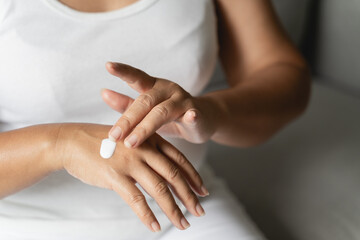 Obraz na płótnie Canvas Woman applying body lotion moisturizer on her hands.