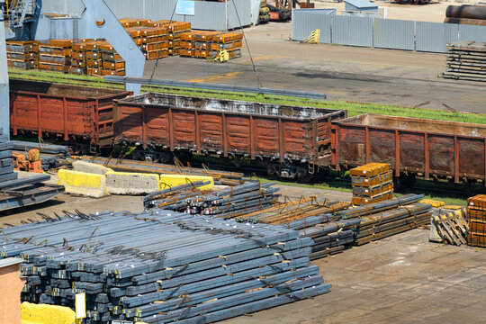industrial infrastructure of the seaport, a warehouse by the sea with railway wagons, iron billets, metal structures, the concept of marine cargo transportation