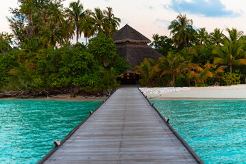 pier leading to the island at sunrise in the Maldives, the concept of luxury travel