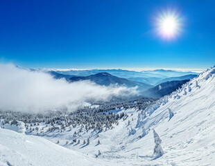 Beautiful sunny winter landscape in thу mountains. Mountain and fir trees covered with snow and clouds.