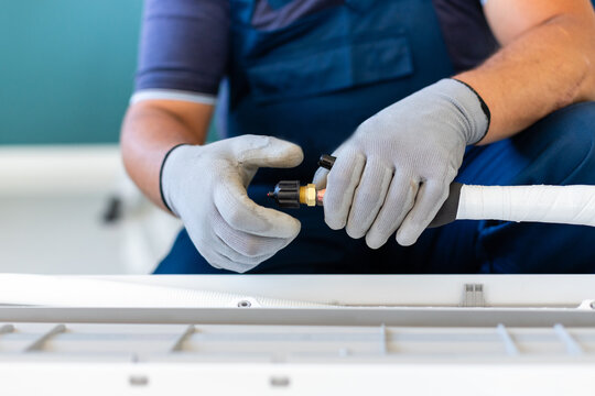 Male technician prepares tools to quickly connect cooling hose to air conditioner.