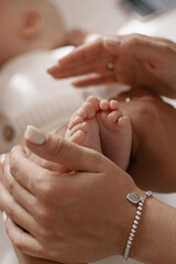 Mother holding newborn baby feet in hands. Mom taking care about infant child after taking bath. Parents c