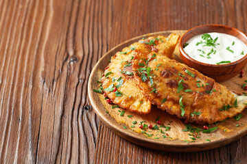 Traditional cheebureki, served on a wooden plate with sauce.