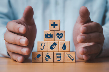 Businessman  hand protecting  to healthcare icons on wooden block cube for health insurance and...