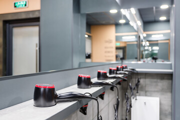 Close up of stand in washroom in gym on which are placed in row many hair dryers.