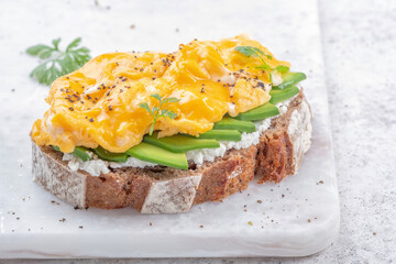 Scrambled eggs with avocado and cream cheese on toast. Breakfast food