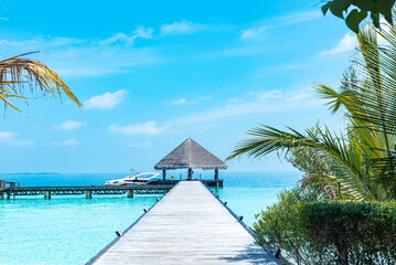 wooden pier in the sea at day time with blue sky and beautiful clouds in the Maldives, the concept of luxury travel