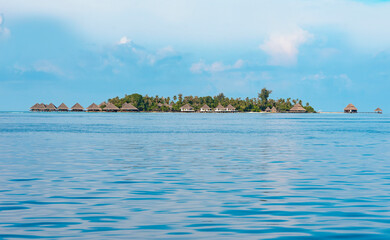 view from sea to island and water villas at day time with blue sky and beautiful clouds in the Maldives, the concept of luxury travel