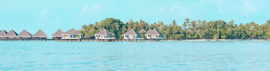 Fototapeta na wymiar view from sea to island and water villas at day time with blue sky and beautiful clouds in the Maldives, the concept of luxury travel, banner