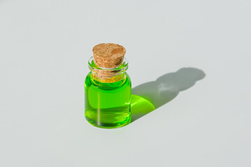 Green liquid in a small jar with a stopper. The shadow of a mysterious container on a white background.