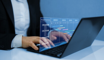 Project manager working on laptop and updating tasks and milestones progress planning with Gantt chart scheduling interface for company on virtual screen. 