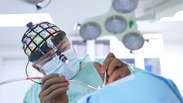 Professional otolaryngology surgeon inputs instruments into patient's nose. Low angle view. Blurred background.