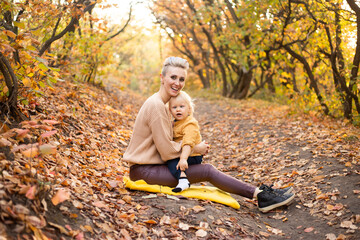 Mother sitting with her little son in autumn park