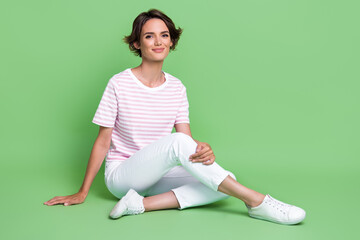 Photo of pretty cute lady dressed nice clothes outfit sit floor relax rest good mood free time isolated on green color background