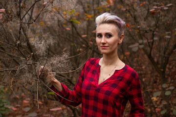 smiling mysterious woman with short hair in autumn forest background with withered trees