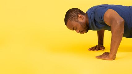 African American Man Doing Push Ups Exercising Over Yellow Background