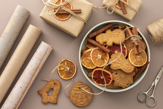 Preparing to decorate your home for Christmas, gift paper and dry citrus fruits with gingerbread cookies on a pastel powdery background