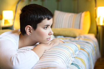 Young sad woman lying in bed