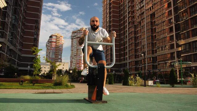 Outdoor gym.The fight against excess weight. A man trains on a stationary exercise bike in the yard of the house.