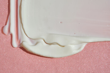 White cosmetic cream on a pink background.
