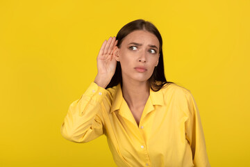 Concerned Female Eavesdropping Holding Hand Near Ear Over Yellow Background