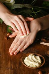 Closeup view of woman's hands applying unrefined shea butter cream on hands, moisturizer, hydration.