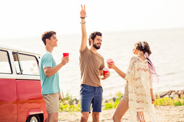 Photo of three excited positive fellows hold plastic drink cups demonstrate v-sign spend vacation...