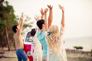 Photo of positive excited hippie people company riding retro van rising arms together outside seaside beach