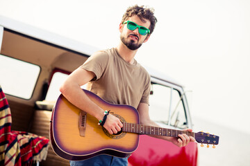 Photo of carefree peaceful person hands hold play acoustic guitar near vintage van spend pastime outside