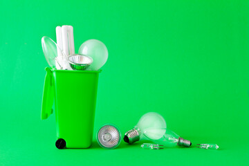 Green living concept: diverse old halogen and fluorescent light bulbs in and around a recycling...