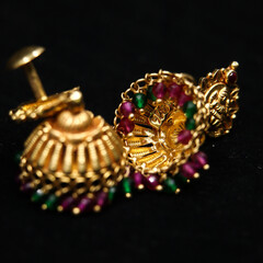 antique earrings called jhumkas made of gold with precious stones from a vintage collection isolated in a black background