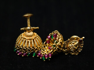 antique earrings called jhumkas made of gold with precious stones from a vintage collection isolated in a black background