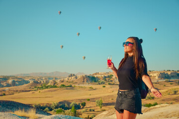 Tourist girl standing and looking to hot air balloons in Cappadocia, Turkey.Happy Travel in Turkey...