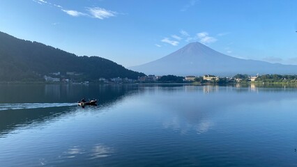 Boat ride across the lake Kawaguchiko with beautiful clear Mt. Fuji view, sunny day with blue sky and the clear tip of the mountain, year 2022 August 27th, 6:27am Yamanashi prefecture, Japan
