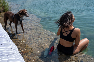 Chica joven con perro bañándose en el rio, mujer en bikini, baño para la calor del verano