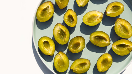 Whole and halves of a blue plums lie on a plate. Autumn harvest. Preparatory stage for making jam, home baking or freezing for the winter.