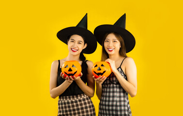 Asian women in halloween concept costume wearing witch hat holding orange pumpkin lantern posing on...