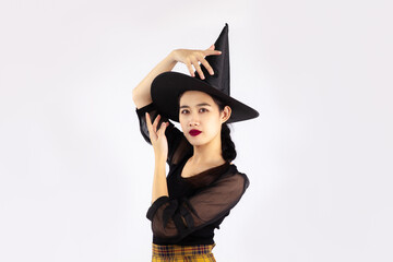 Young asian woman in black halloween costume wearing witch hat posing on white background.