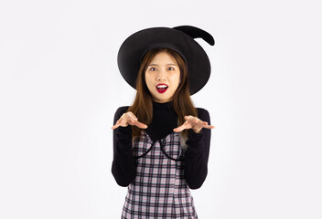 Young asian woman in black halloween costume wearing witch's hat posing on white background.