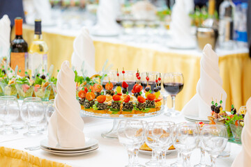 Glasses of red wine, delicacies, snacks and desserts on luxuriously served buffet tables. Restaurant business, catering.
