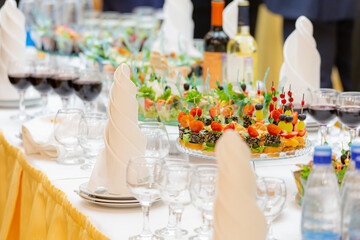 Glasses of red wine, delicacies, snacks and desserts on luxuriously served buffet tables. Restaurant business, catering.