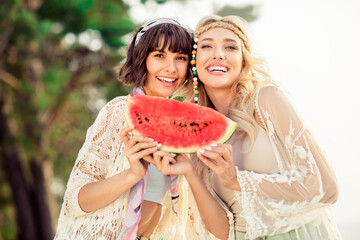 Photo of two cheerful adorable girls hold watermelon slice toothy beaming smile pastime outside