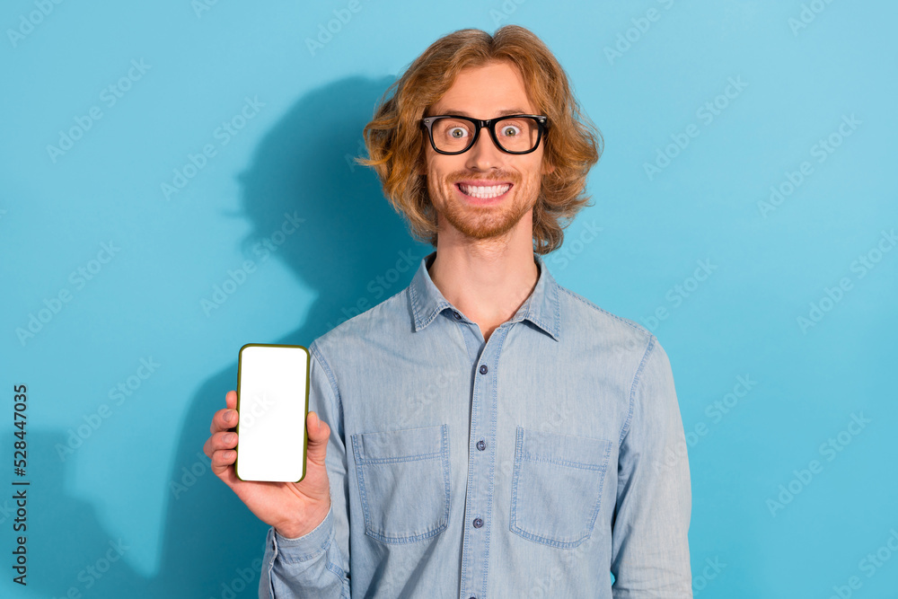 Sticker Portrait of cheerful funky guy hold demonstrate empty space telephone screen ui menu isolated on blue color background