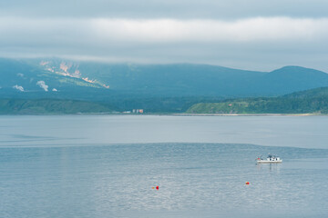 sea bay with foggy mountains in the background, view of the Mendeleev volcano on a cloudy day