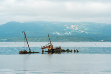 sunken ship against the backdrop of a sea bay with foggy mountains in the background