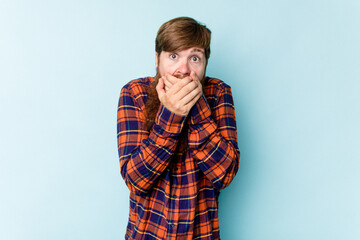 Young caucasian red-haired man isolated on blue background scared and afraid.