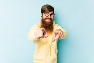 Young caucasian red-haired man isolated on blue background pointing to front with fingers.