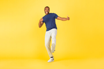 Fototapeta na wymiar Happy African American Male Gesturing Thumbs Up Over Yellow Background
