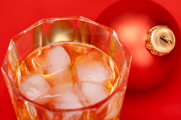Glass of whiskey with christmas bauble on red background christmas drink concept