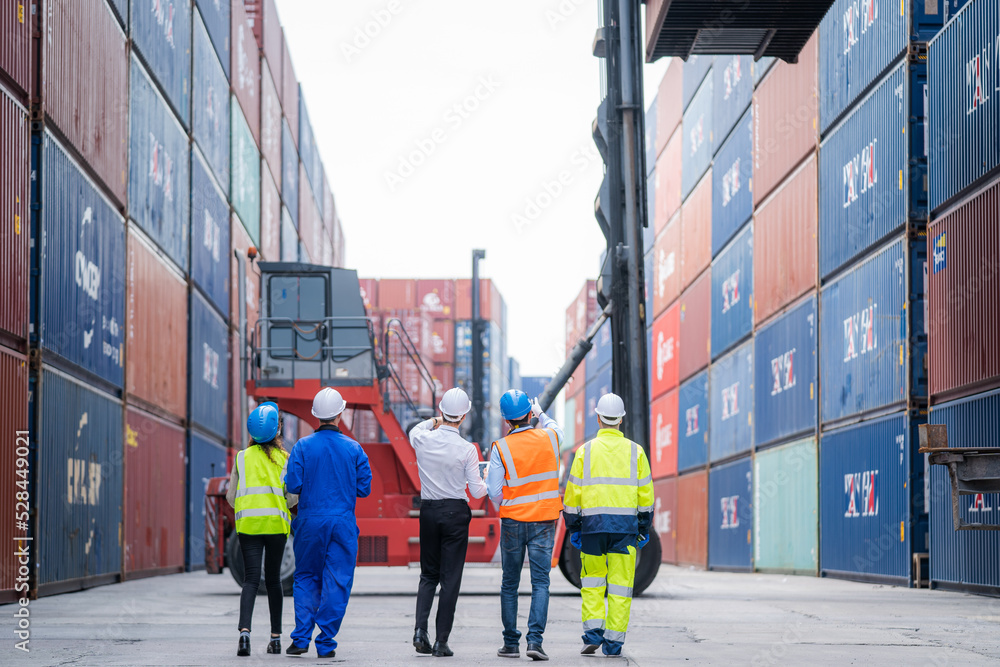 Poster Manager and professional container yard workers checking stock for loading in the container yard warehouse,Logistic shipping yard business.